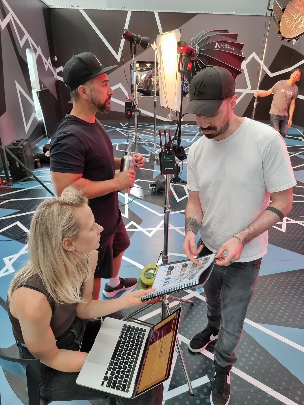 Checking a lookbook and laptop with the crew on set