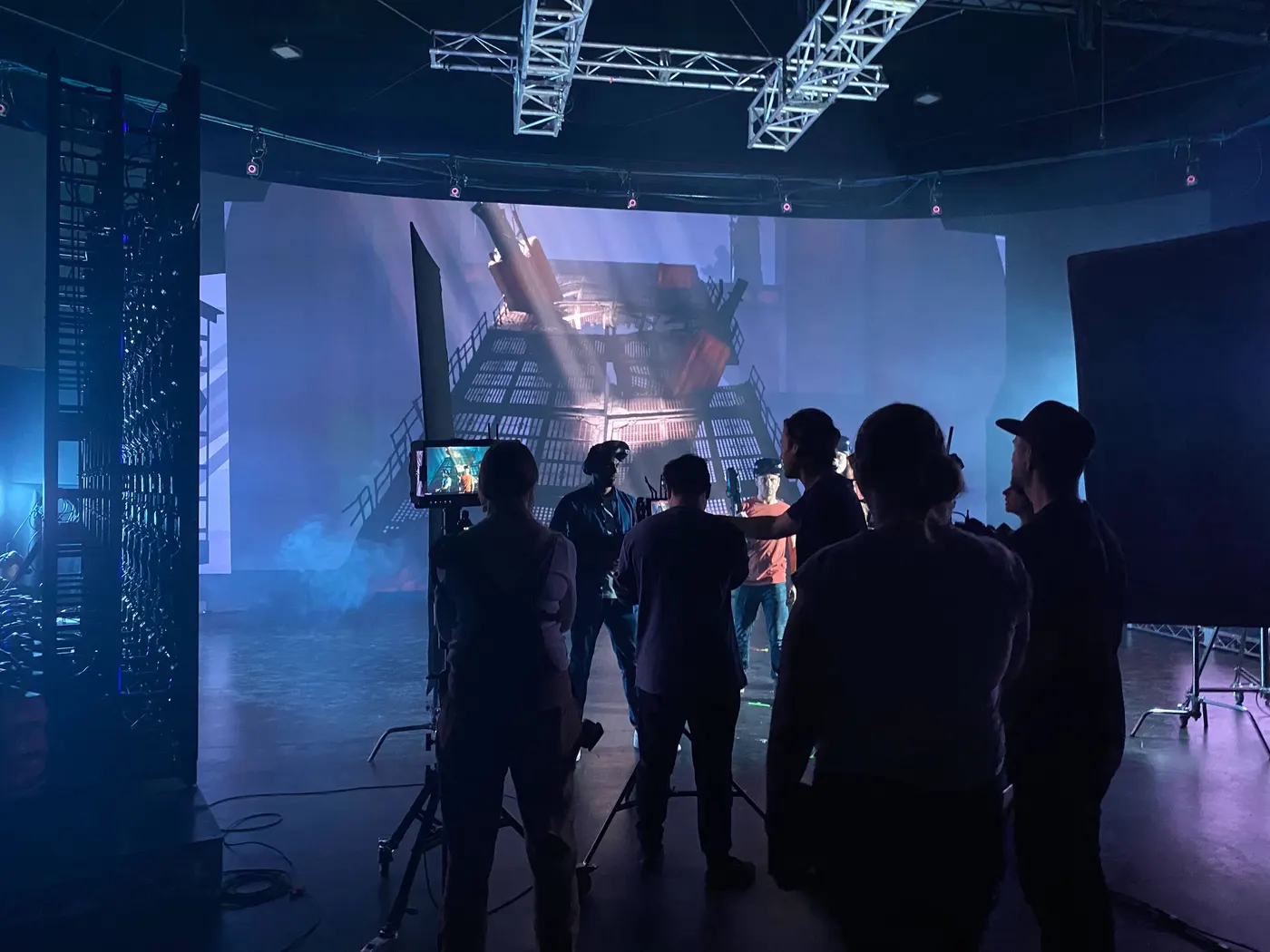 Crew silhouetted against an industrial scene on the LED wall